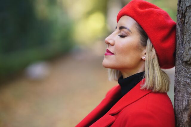Close-up profile picture of a middle-aged woman leaning against a tree trunk with her eyes closed. Close-up profile picture of a middle-aged woman leaning against a tree trunk with her eyes closed.